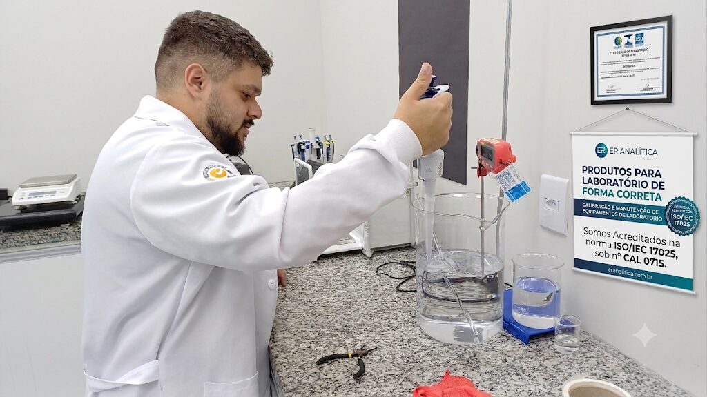 Analista em laboratório operando cromatógrafo a gás em bancada, ao lado de banner e certificado de acreditação ISO/IEC 17025 do Inmetro para serviços de calibração.